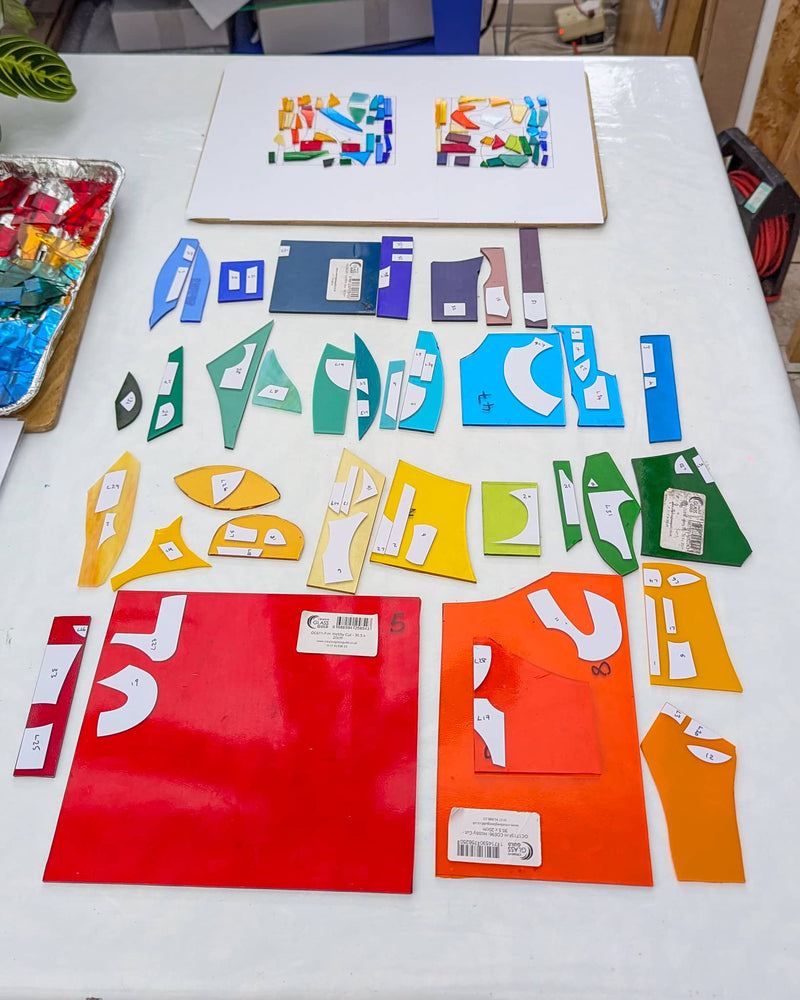 Work in progress on commissioned Alphabet glass Miniatures showing individually cut glass pieces prepared before assembly