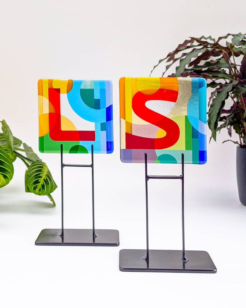 Pair of commissioned 5-inch contemporary glass Alphabet Miniatures by Linda Rossiter displaying the collector's initials on matching metal stands