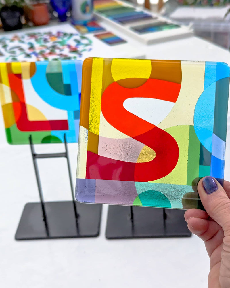 Close-up of commissioned 5-inch Alphabet glass Miniature featuring the letter S with an abstract Hard Edge background