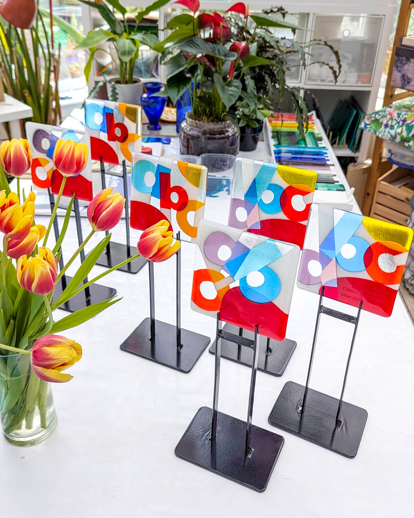 'Chicka Chicka' fused glass awards with bold alphabet designs on stands