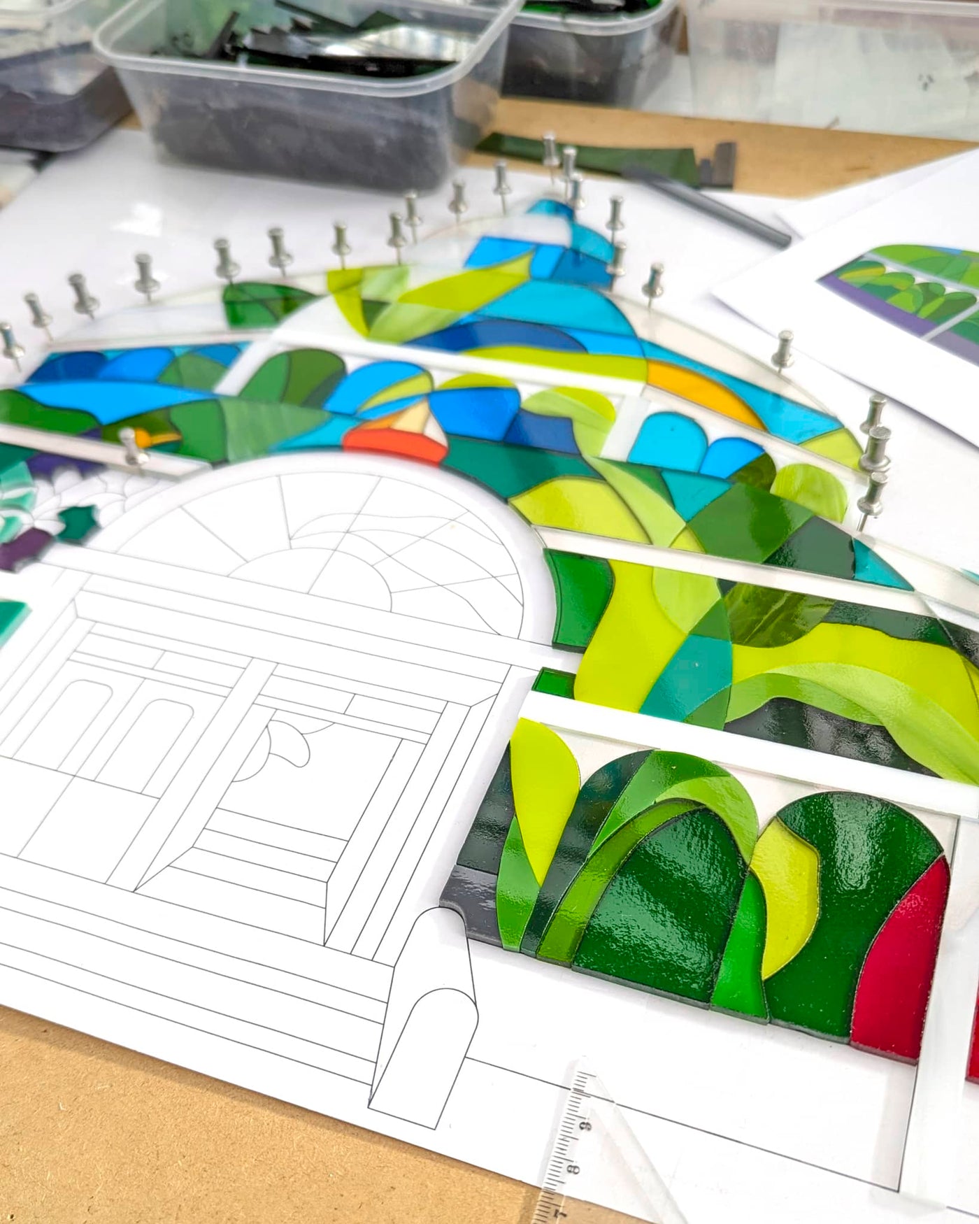 Work in progress on 'Palm House' showing individually cut glass pieces carefully positioned before kiln firing, with the architectural glasshouse and planting still being completed