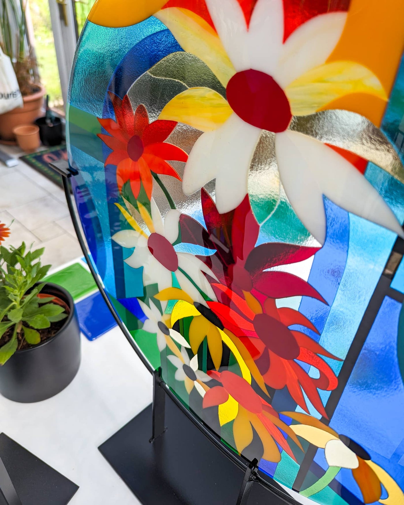 Close-up of the 'Abundance' contemporary Hard Edge glass roundel showing overlapping flower forms, bold colour relationships and individually cut glass pieces