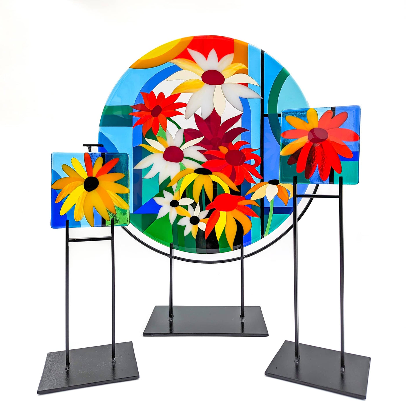 'Abundance' contemporary Hard Edge glass roundel with two matching floral miniatures on steel stands, featuring a vibrant arrangement of colourful flowers
