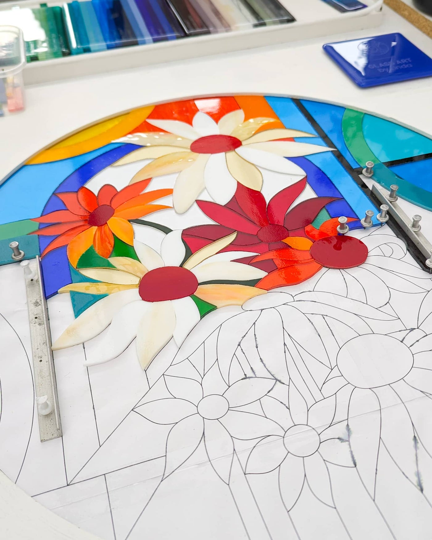 Work in progress on the 'Abundance' contemporary Hard Edge glass roundel showing individually cut glass pieces being positioned before kiln firing, with the remaining floral design still to be completed