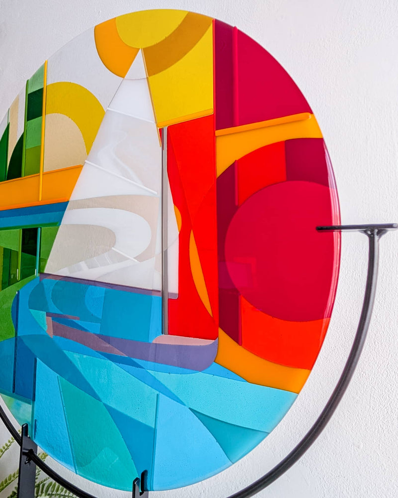 Close-up of Beaulieu River fused glass art showing the scow sailboat, blue water and bold red, orange and yellow geometric shapes