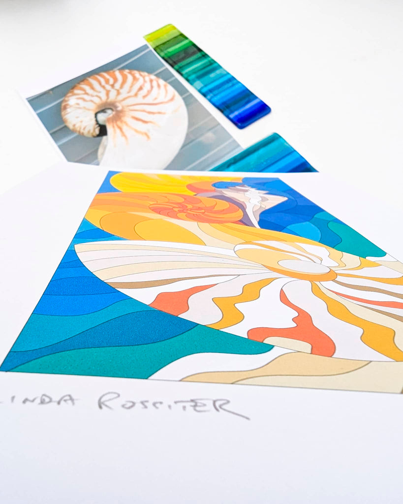 Glass art design sketch signed by Linda Rossiter, featuring vibrant flowing shapes in orange, blue, and cream tones, alongside colour samples and a shell – part of the early concept stage at Glass Art by Linda
