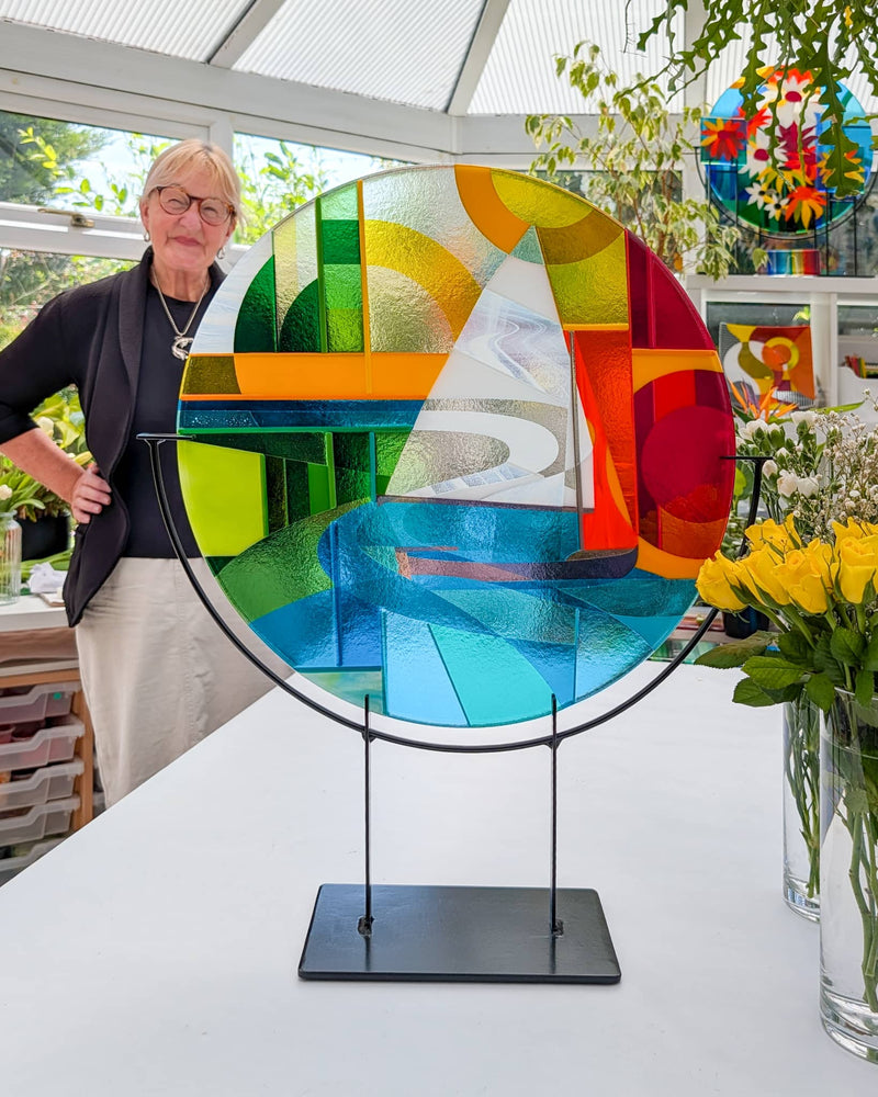 Linda Rossiter with the finished Beaulieu River Hard Edge fused glass roundel on its metal stand