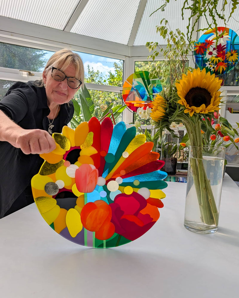 Linda Rossiter presenting the completed colourful Sunshine Hard Edge fused glass wall panel in her studio