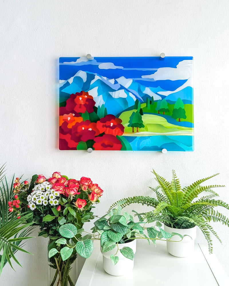 Shangri-La fused glass landscape wall art displayed above flowers and green plants in a light interior
