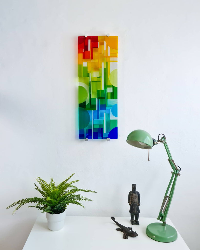 Spectrum colourful glass wall panel displayed above a white table with a fern and green desk lamp