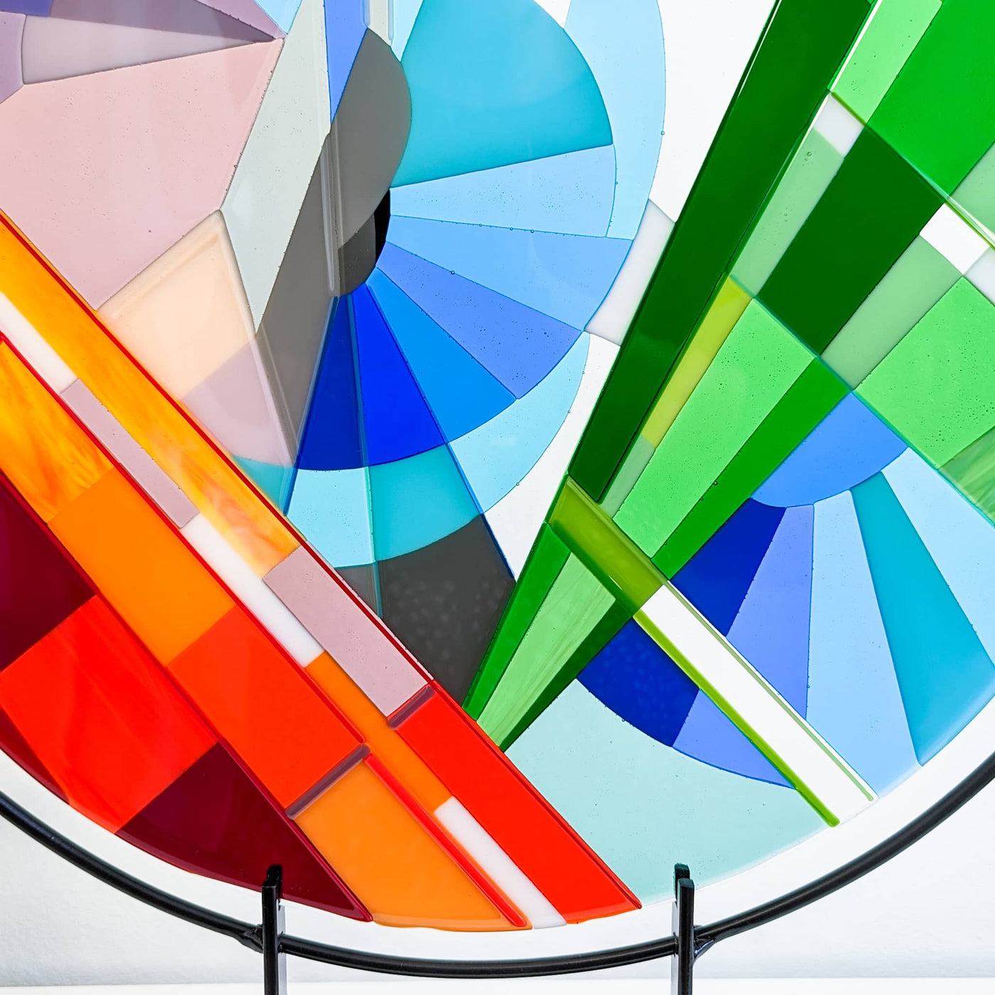 Close-up of 'Stairs' contemporary Hard Edge glass roundel showing the sweeping circular forms, intersecting lines and vivid colour transitions