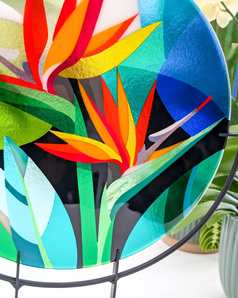 Close-up of the commissioned contemporary Hard Edge glass birds of paradise artwork showing layered geometric leaves and vibrant orange flowers created from individually cut glass pieces
