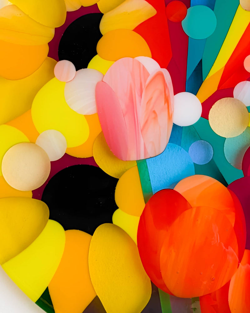 Close-up of colourful fused glass flowers in the Sunshine anniversary commission, with pink tulip and yellow sunflower shapes