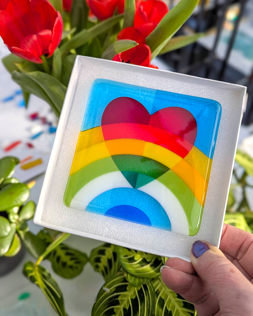 Fused glass miniature featuring a red heart above a rainbow of bold colours on a blue background, displayed in a white gift box