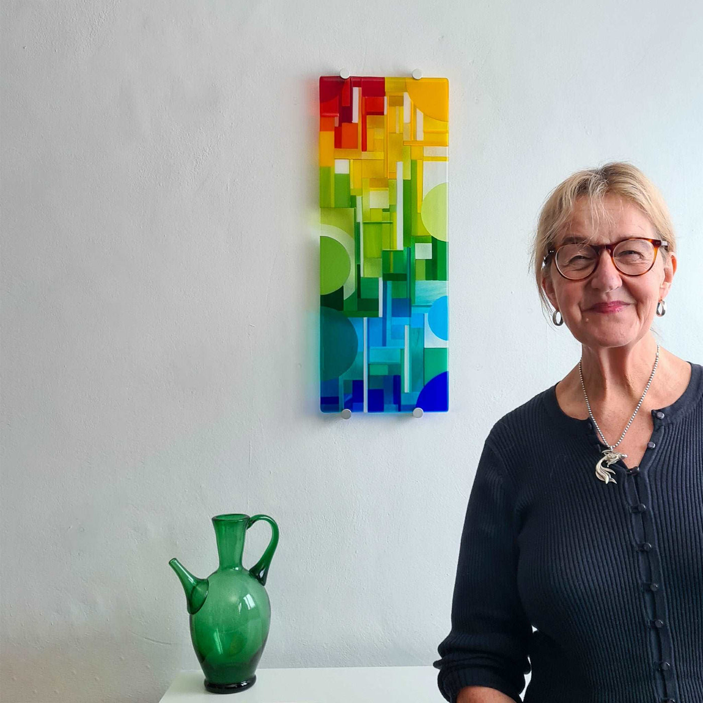 Linda Rossiter with the completed 'Spectrum' contemporary Hard Edge glass wall artwork displayed in her studio