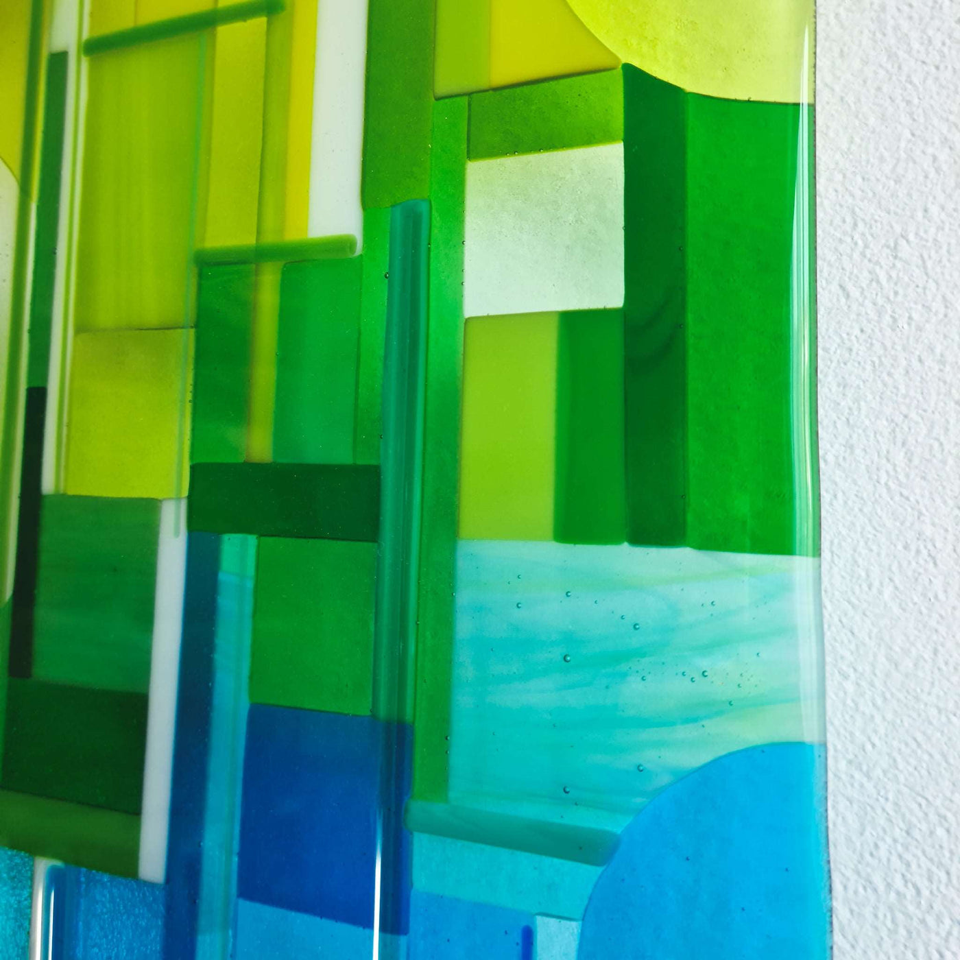 Close-up of 'Spectrum' contemporary Hard Edge glass wall artwork showing layered geometric blocks of green and blue glass with glass noodles creating strong vertical lines